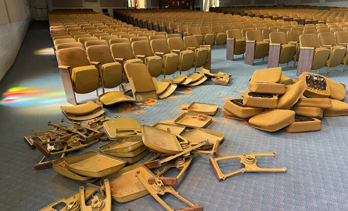 Old and worn pew-style church seating being removed during a remodel.