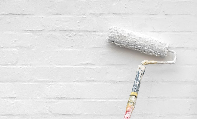 Image of bricks being painted white with a roller brush