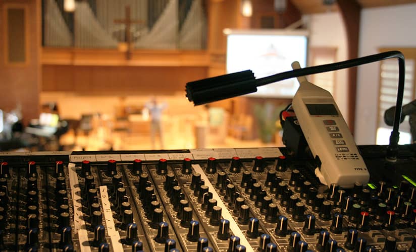 Audio control booth with worship service in the background