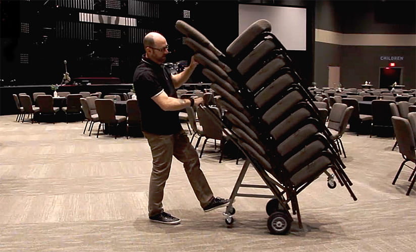 person moving chairs with a cart