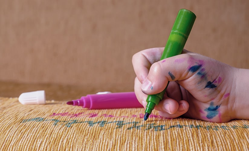 Primer plano de un niño coloreando muebles con marcadores.