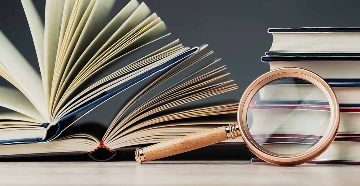 Pile of books with a magnifying glass