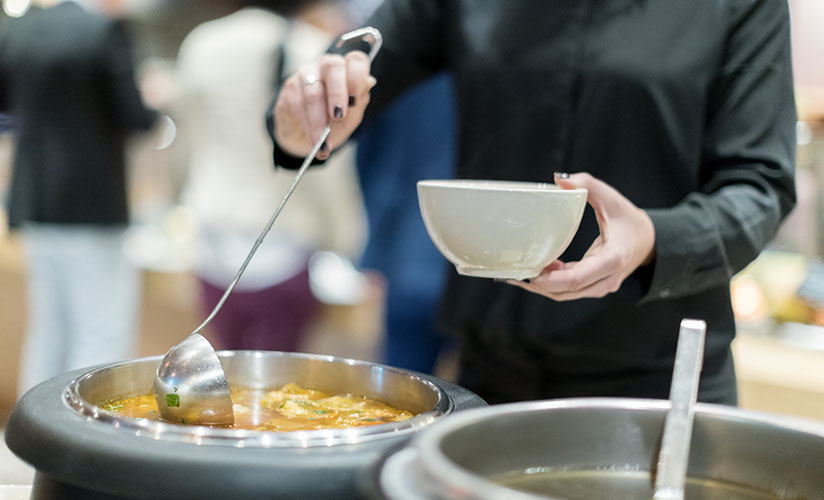 gros plan d'une personne versant de la soupe dans un bol