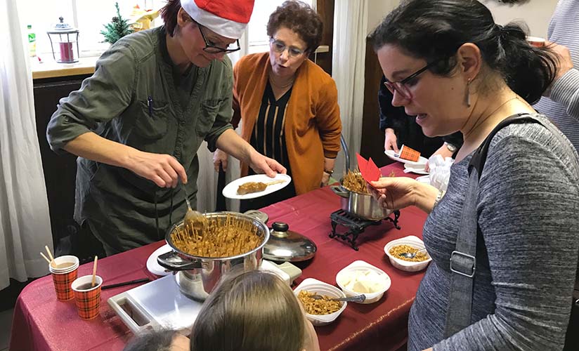 les participants à l'événement reçoivent de la nourriture à une table de style potluck