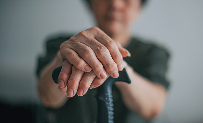 Close up of hands resting on a cane