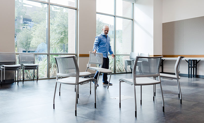 A man organizing chairs into a circle